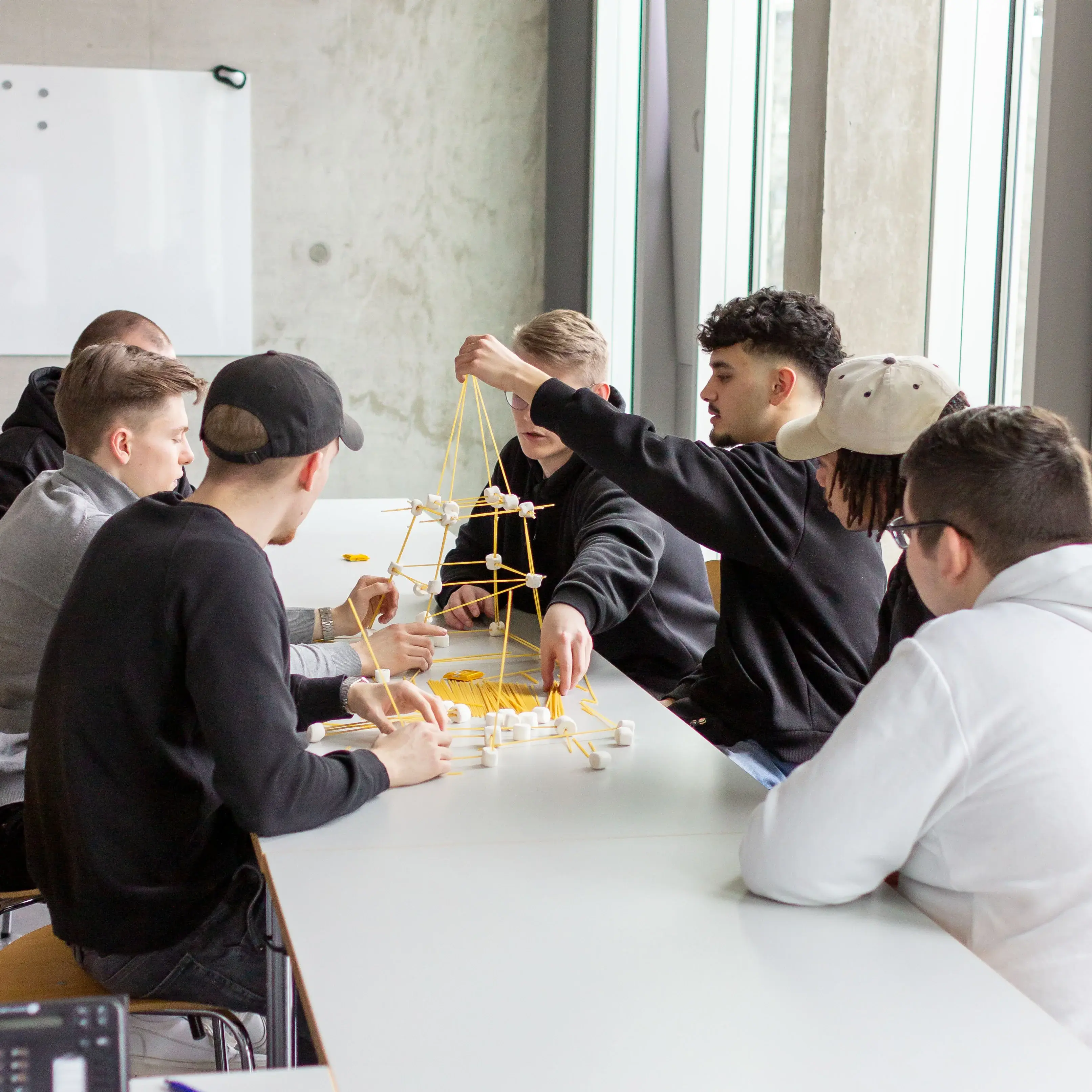 Studierende arbeiten gemeinsam an einer Challenge den höchsten Turm zu bauen.